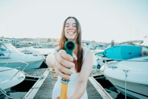 A young cheerful woman cleaning a classic sailing yacht with sweet water after sailing i